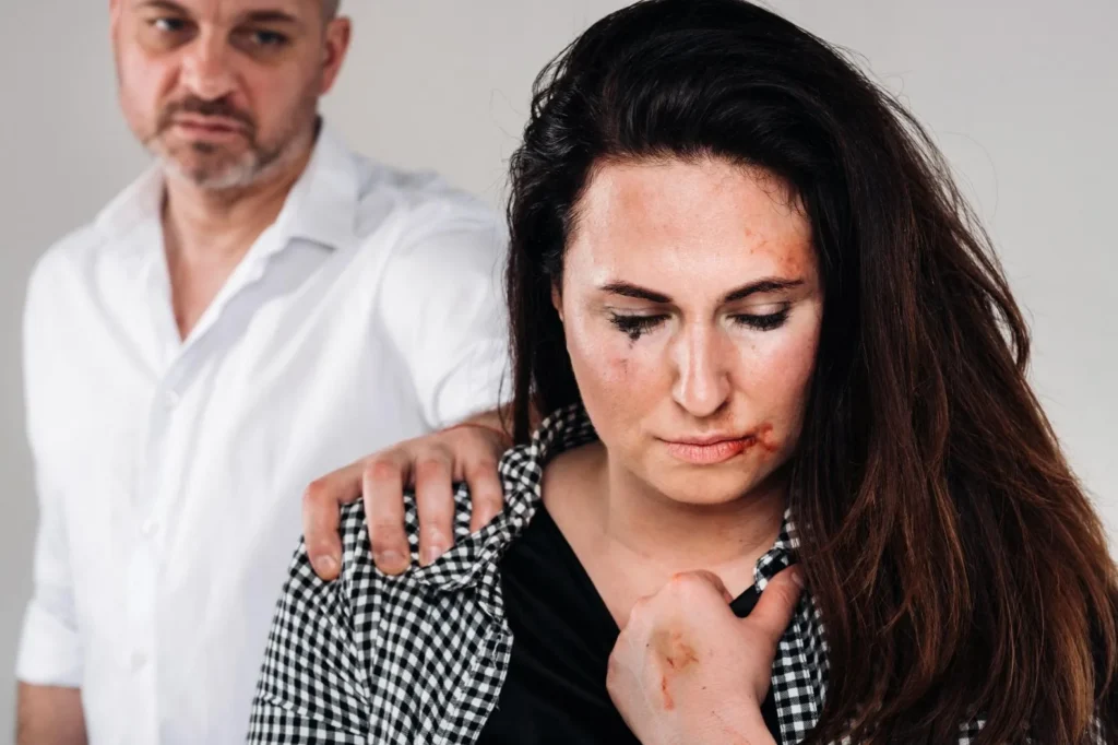 Battered woman with a man grabbing her shoulder