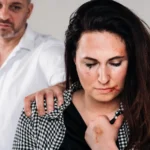 Battered woman with a man grabbing her shoulder