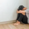 Depressed young man sitting on the floor in the corner of their room