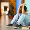Little boy sitting in the corner with his head in his hands