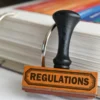 Regulations stamp sitting on top of a pile of papers