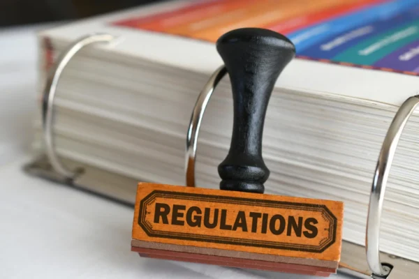 Regulations stamp sitting on top of a pile of papers