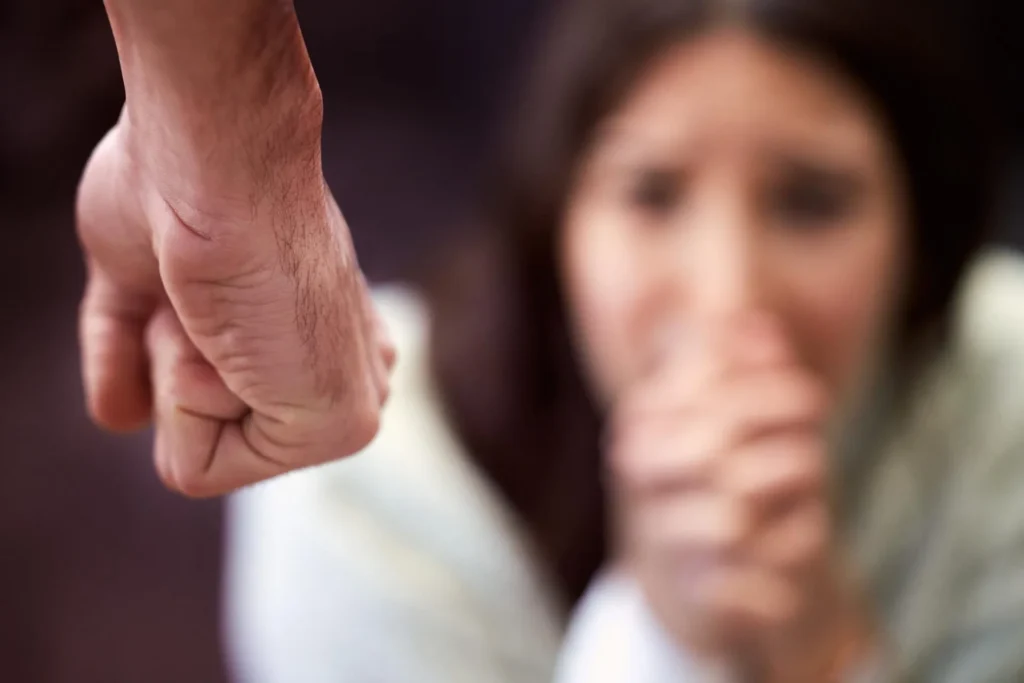 Clenched fist of a man with a woman in the background scared